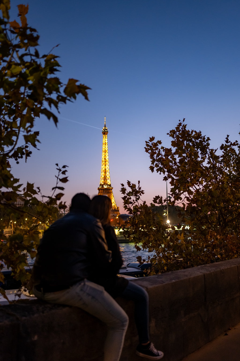 The Eiffel Tower at dusk behind a seated visitor