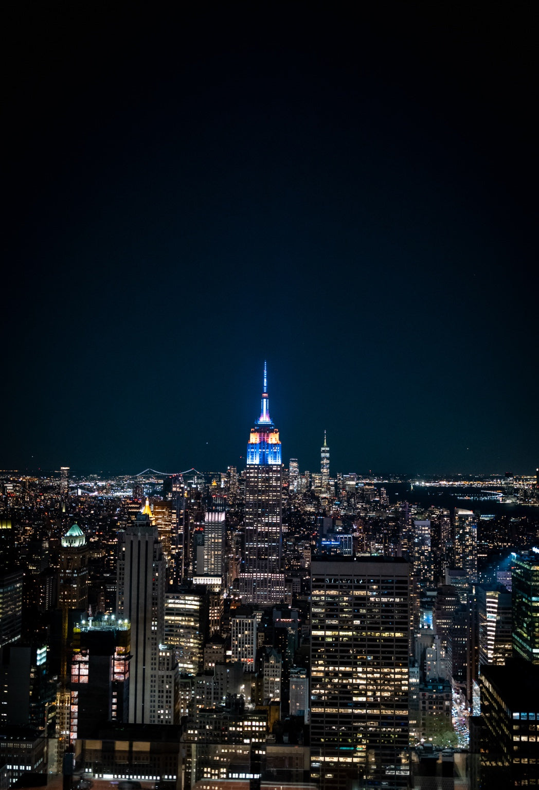 New York skyline with the Empire State Building lit blue at night