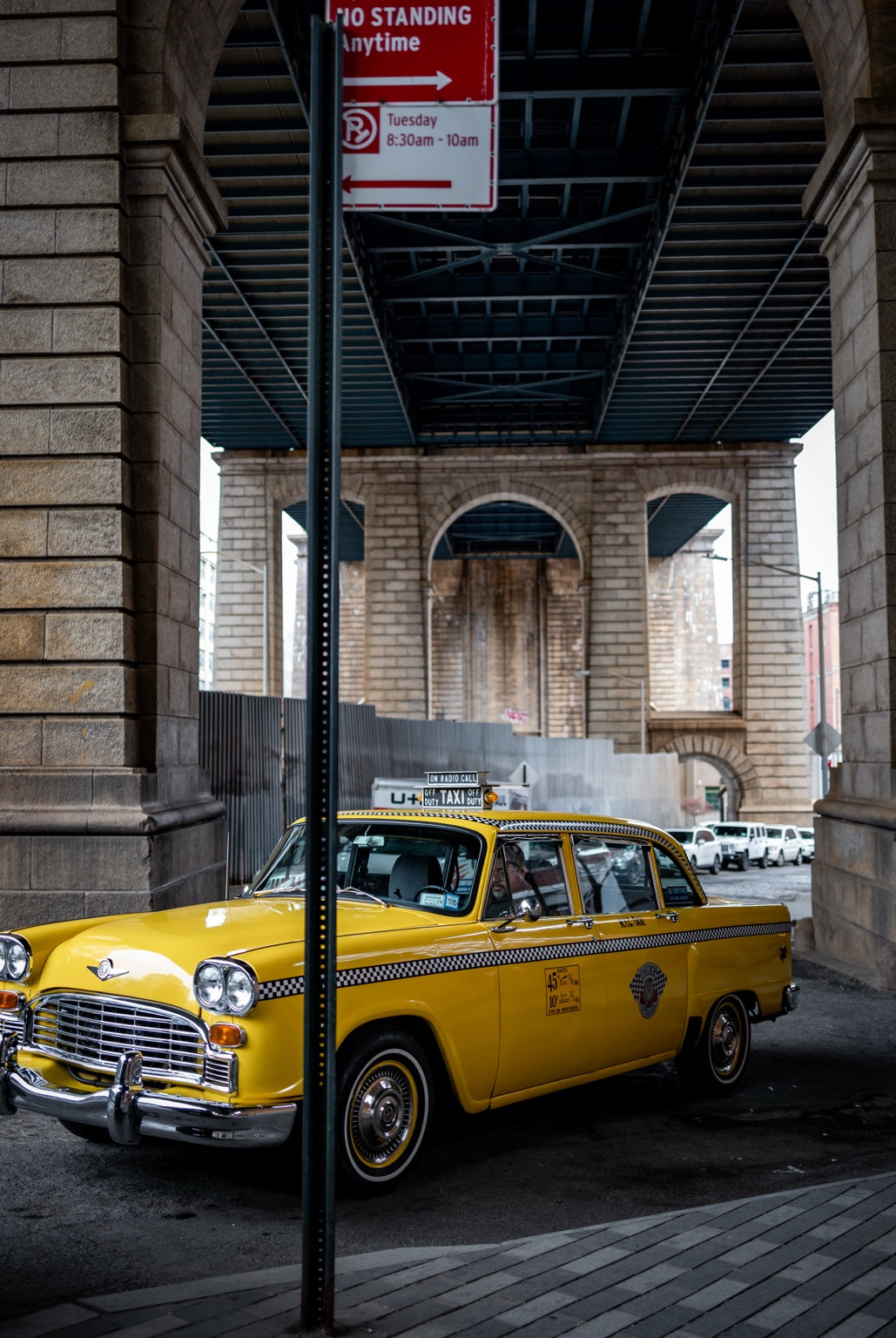 A yellow taxi beneath a New York bridge