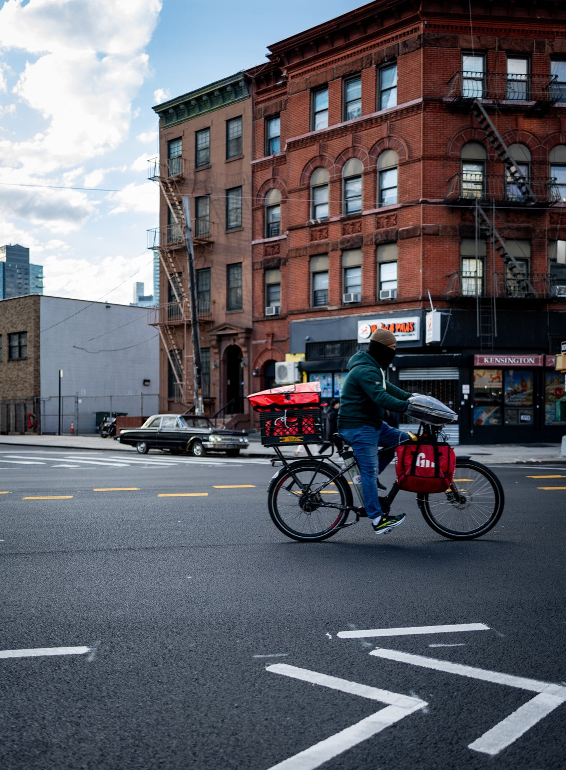 A cyclist passing red brick buildings