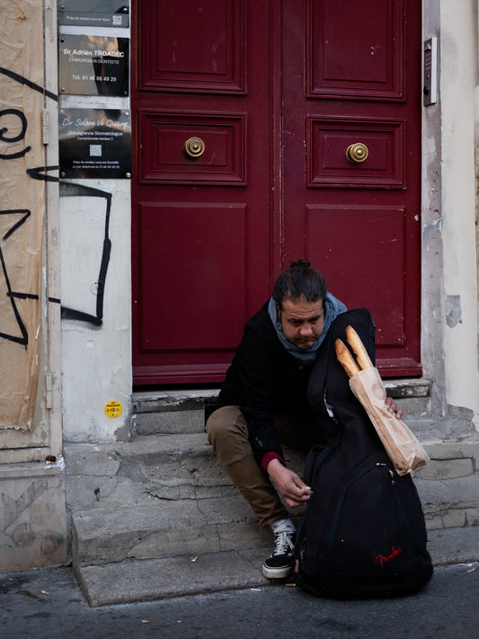 A man seated by a red doorway in Paris