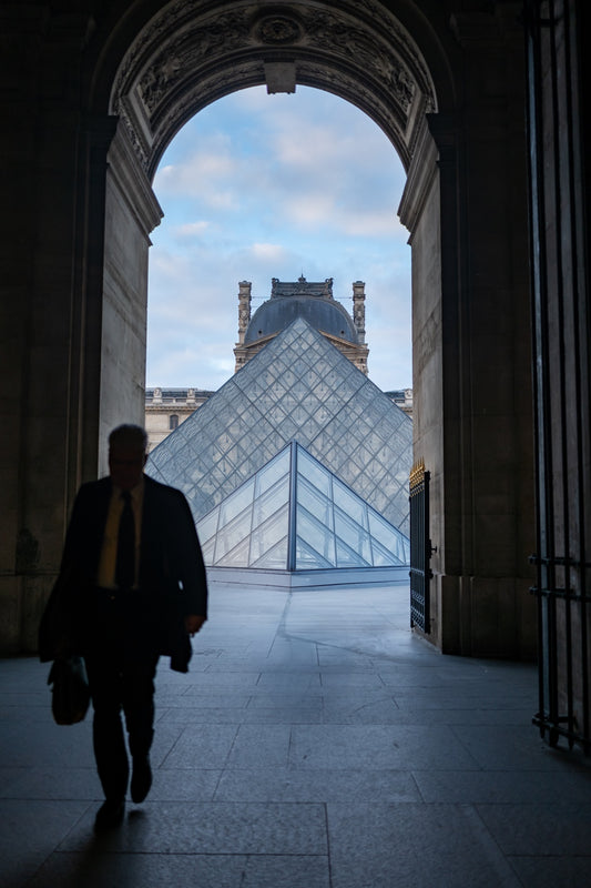 A person walking through an arch near the Louvre in Paris
