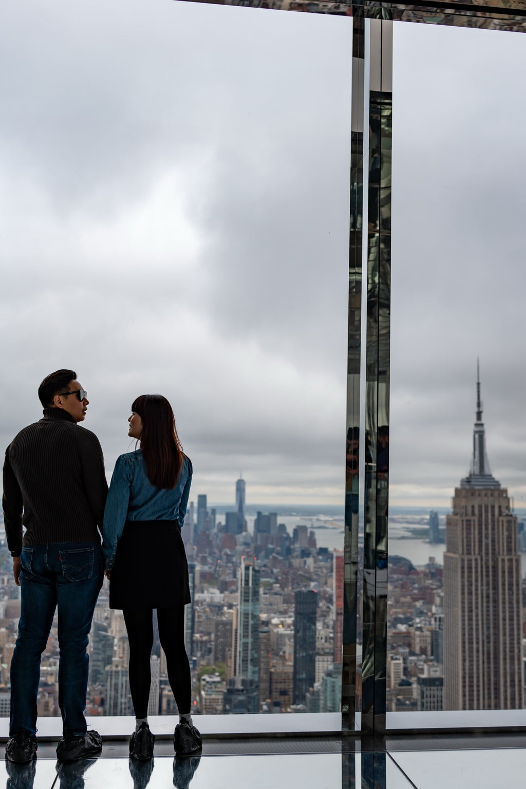 Two people at a New York observation deck with the Empire State Building beyond