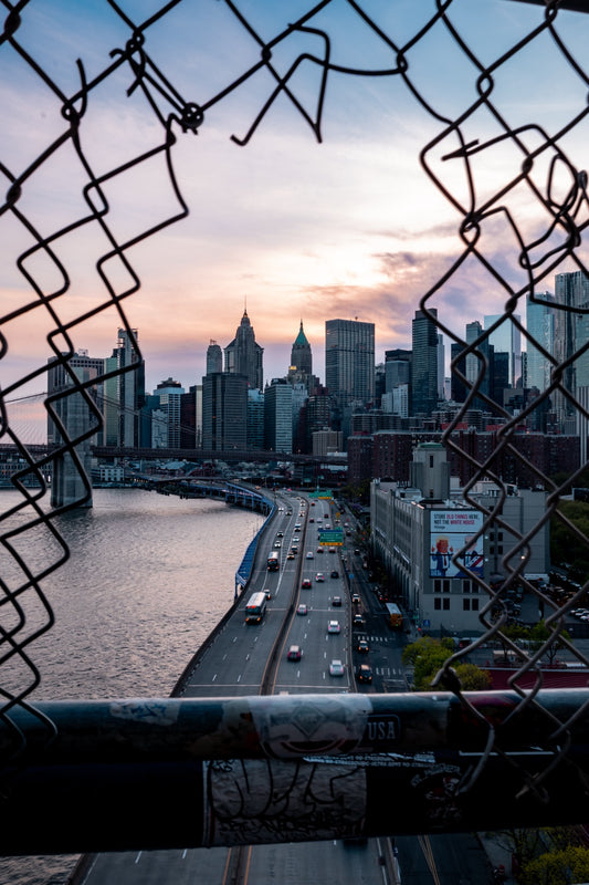 New York skyline and road framed by a chain-link fence